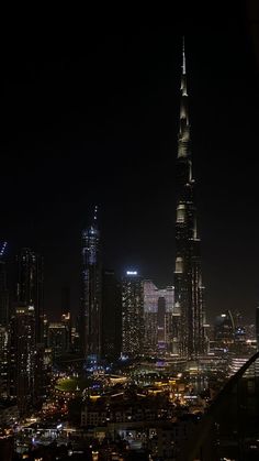 the city skyline is lit up at night, with skyscrapers in the foreground