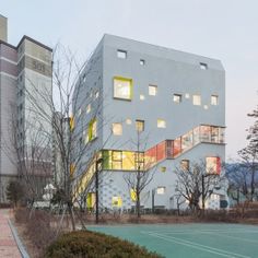 a tennis court in front of two buildings with windows and balconies on each side