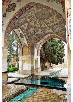 the inside of an ornate building with a pool in front of it and trees on either side