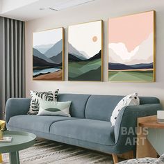 a living room with three paintings hanging on the wall and two couches in front of them