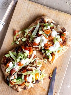 two flatbread pizzas on a cutting board with a knife and fork next to them