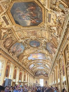 many people are walking around in a large room with paintings on the walls and ceiling