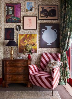 a living room with pictures on the wall and a chair in front of a dresser