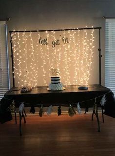 a table topped with a cake covered in frosting next to a wall that has lights on it