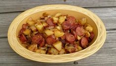 a yellow bowl filled with potatoes sitting on top of a wooden table