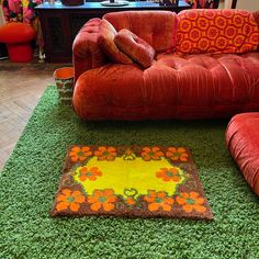 a red couch sitting on top of a green rug