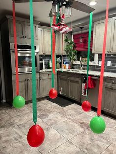 some green and red balloons hanging from the ceiling in a kitchen with granite flooring