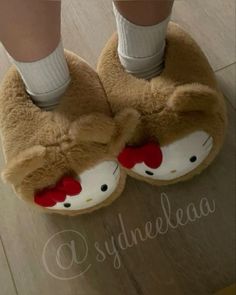 a pair of hello kitty slippers on top of a wooden floor next to a person's feet