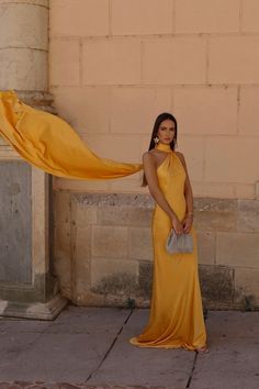 a woman in a long yellow dress poses for the camera