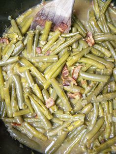 green beans and bacon cooking in a pan with a wooden spoon