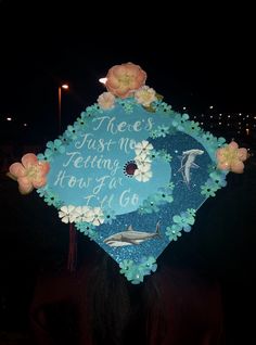 a blue graduation cap decorated with flowers and dolphins on it that says, there's just me telling how far i go