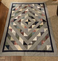 a quilt is laying on the floor in front of a chair and table topper