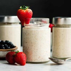 three jars filled with oatmeal and strawberries next to each other on a table