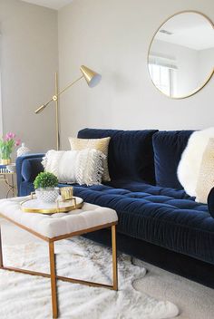 a living room with a blue velvet couch and white fur rugs on the floor