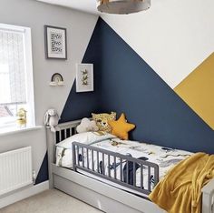 a child's room with a bed and wall painted in blue, yellow and white