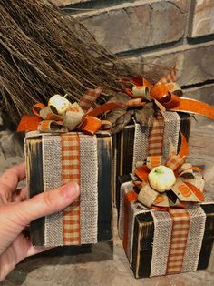 someone is holding two wrapped gift boxes with pumpkins on them