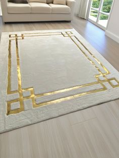 a living room with a white couch and gold trimmings on the rug is shown