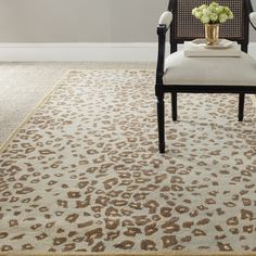 a leopard print area rug with a chair and vase on the floor in front of it