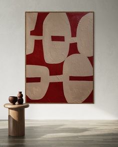 an abstract painting on the wall next to a table with two vases in front of it