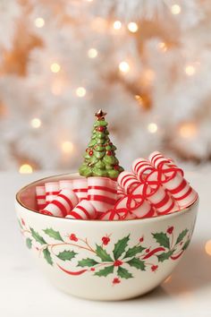 a bowl filled with candy canes next to a christmas tree