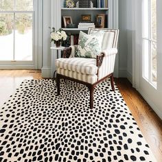 a living room with a chair, bookshelf and rug in front of the window