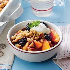 a white bowl filled with fruit and topped with ice cream on top of a blue table