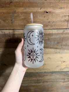 a hand holding a can with sun and moon designs on it