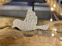 a white bird ornament sitting on top of a wooden table next to string lights