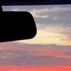 the sun is setting behind some clouds in the sky as seen from an airplane window