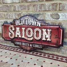 an old town saloon sign on the side of a brick wall next to a tiled floor