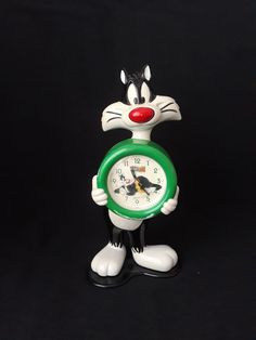 a clock that is shaped like a cat with a green ring around it's neck