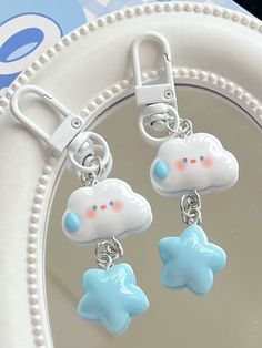 two little blue and white clouds are hanging from a keychain on a plate