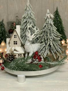 a white deer figurine sitting on top of a table next to christmas trees