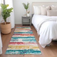 a white bed sitting next to a green plant on top of a wooden floor