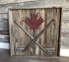 a wooden frame with a red maple leaf on it and two crossed bars in the middle