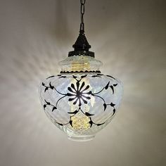 a glass light fixture hanging from a ceiling