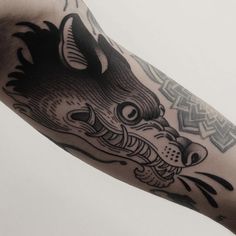 a black and white photo of a wolf tattoo on the arm