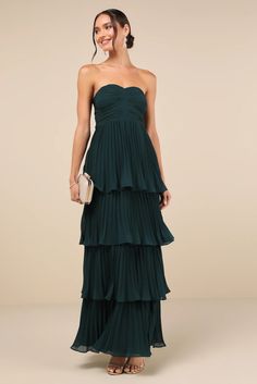 a woman in a strapless green dress with tiered layers and a handbag