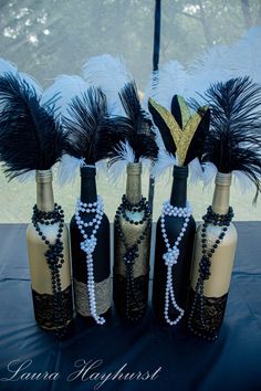 there are five wine bottles decorated with feathers and beads