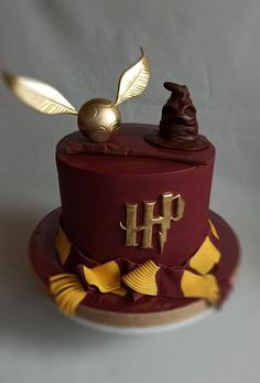 a harry potter birthday cake with gold decorations on top and a hogwarts hat