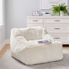 a white bean bag chair sitting on top of a rug in a living room next to a dresser