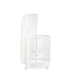 a white crib with a curtain on top