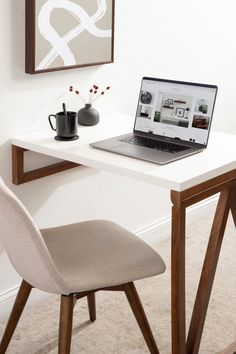 a laptop computer sitting on top of a white desk next to a cup of coffee