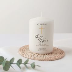 a white candle sitting on top of a wicker coaster next to a green plant