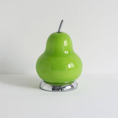 a green apple sitting on top of a metal stand