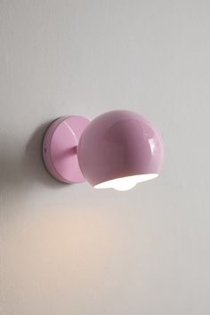 a light that is on the wall next to a white wall with a pink shade