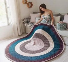 a woman sitting on a couch with a crocheted blanket in the shape of a spiral