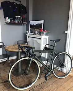 two bikes are parked next to each other in a room with grey walls and wooden floors