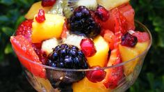 a fruit salad in a glass bowl on top of a table