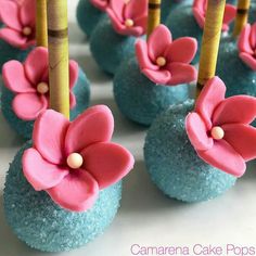 blue cake pops decorated with pink flowers and bamboo sticks